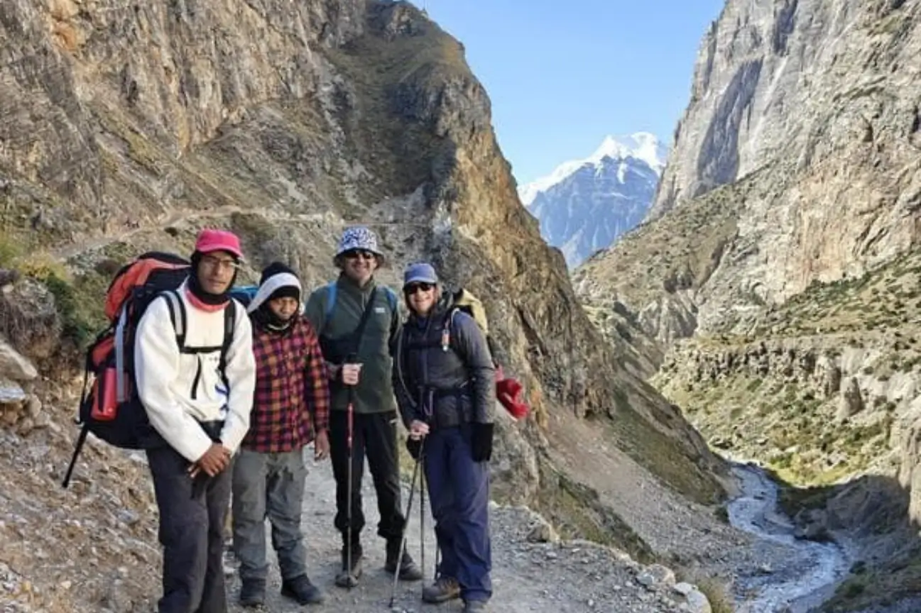 A group of smiling hikers with expert local guides standing on a rugged Himalayan trail during Nepal trek tours.