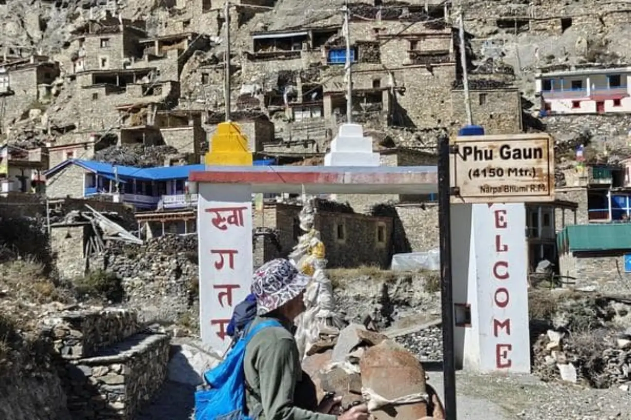 A trekker arriving at a high altitude mountain village gateway during Nepal trek tours.
