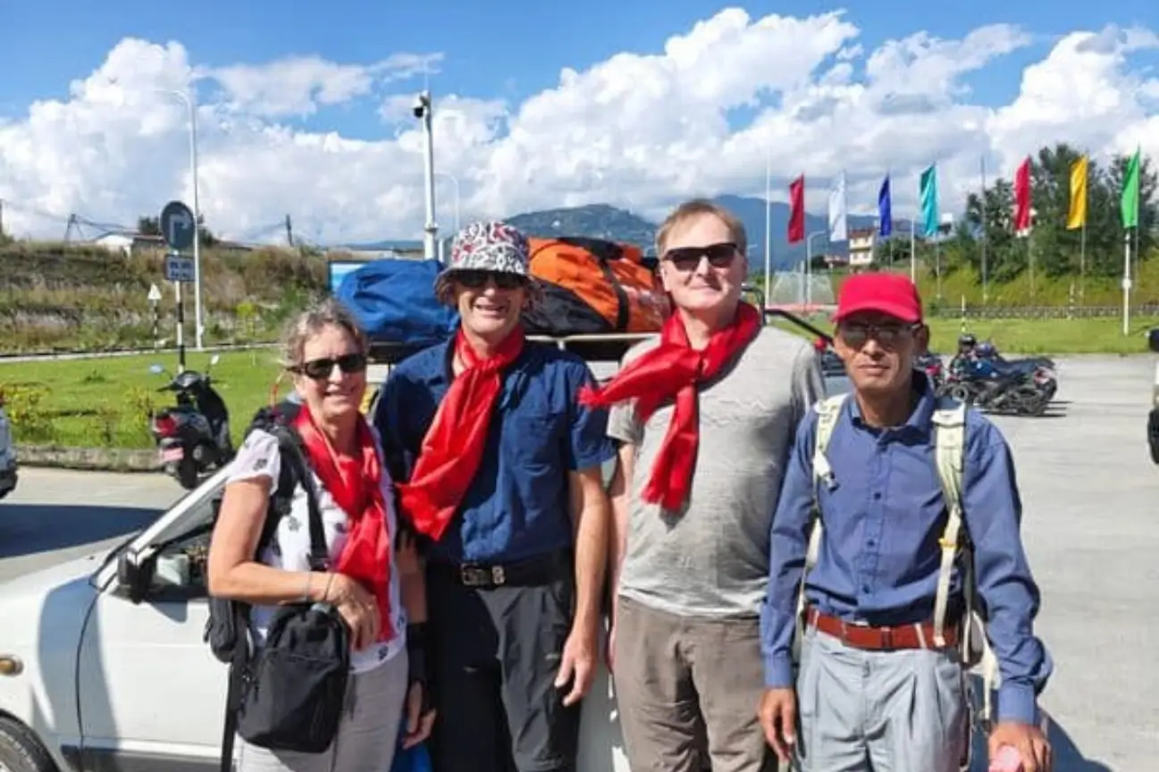 A happy family group wearing traditional red scarves and traveling together during Nepal trek tours.