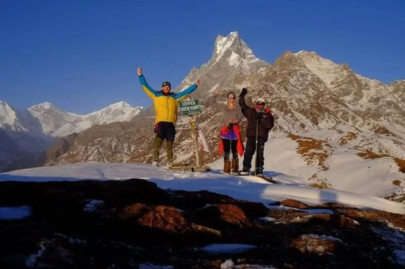 Trekkers celebrating their summit victory at a snow-covered viewpoint during Nepal trek tours.